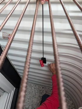 Person installing egress window well grate locks with emergency release in a basement window well.